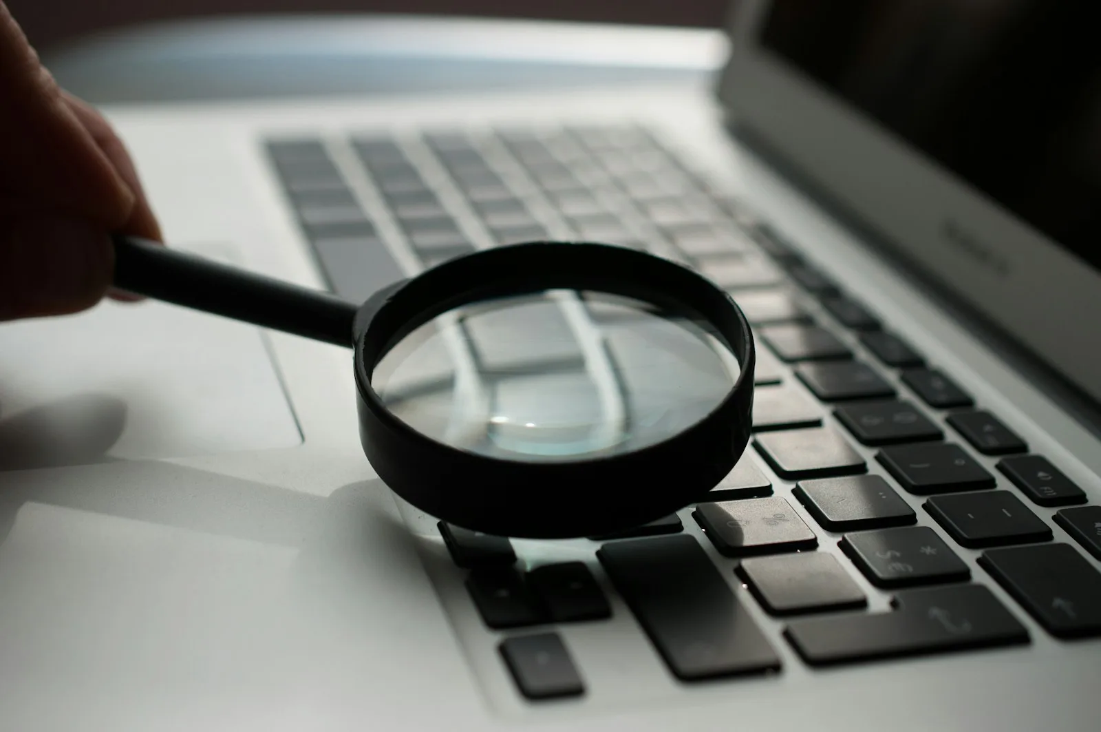 Loupe posée à côté d'un ordinateur portable, illustrant la recherche de mots-clés locaux